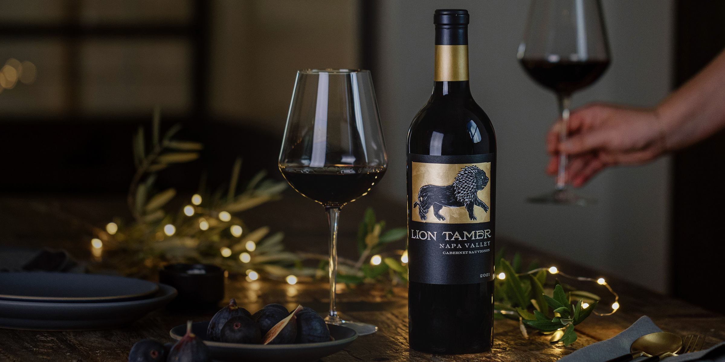 a bottle of cabernet sits on a table spread with foliage and lights